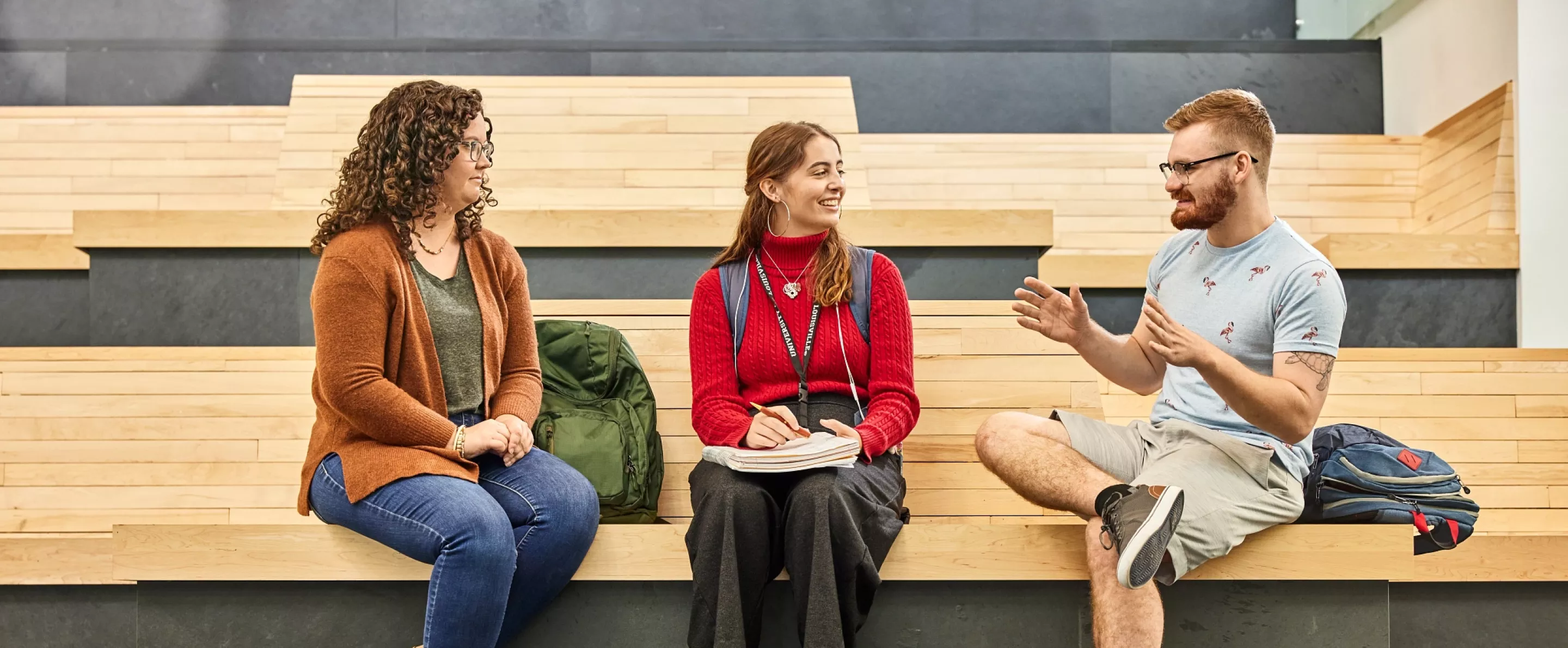 Alison Williams sitting on the wooden benches within the entrance of the Belknap Academic Building