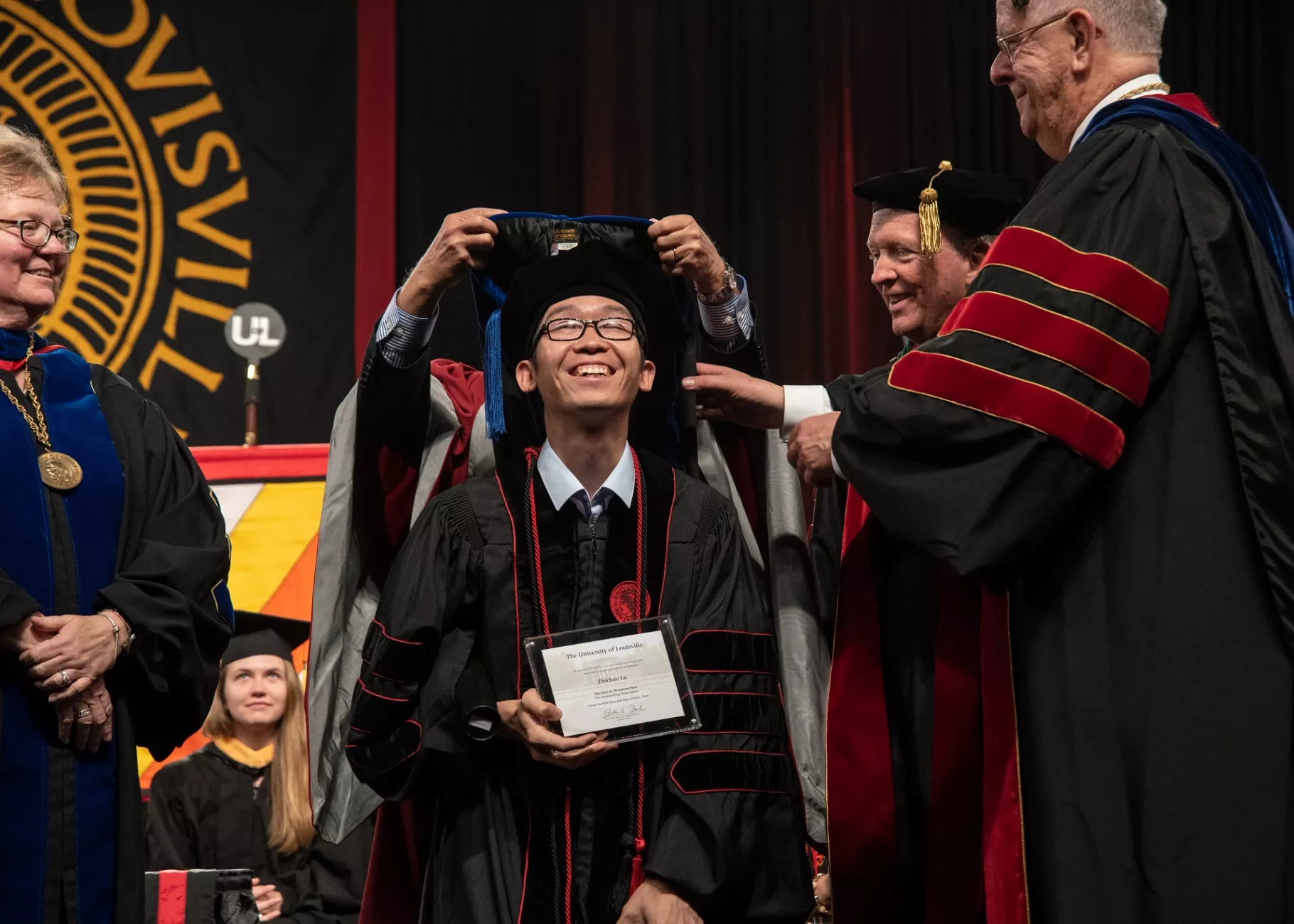 PHD student smiles at the Hooding Ceremony