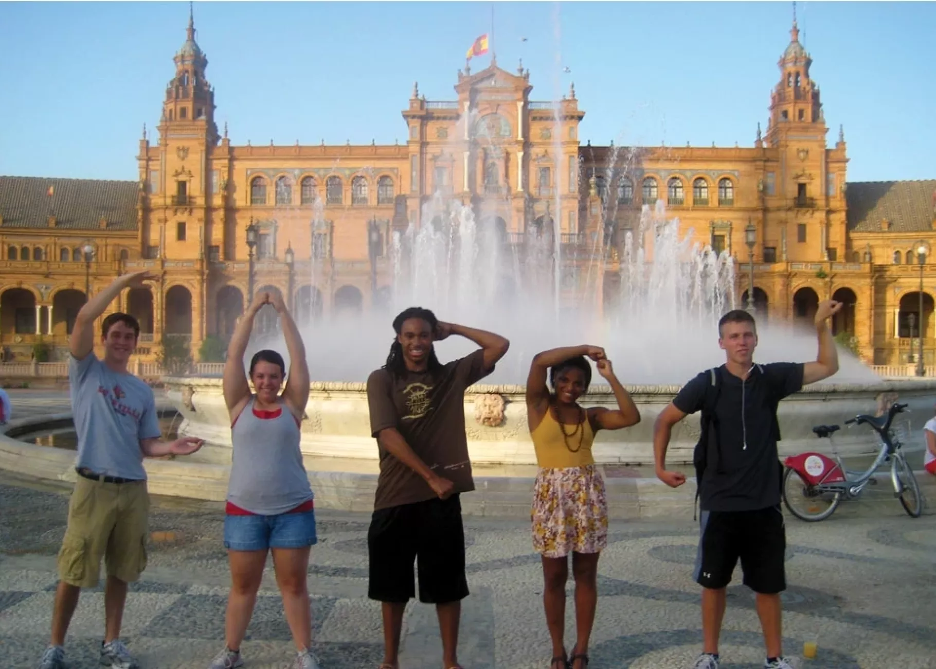 Students posing in front of fountain with arms in the shape of CARDS