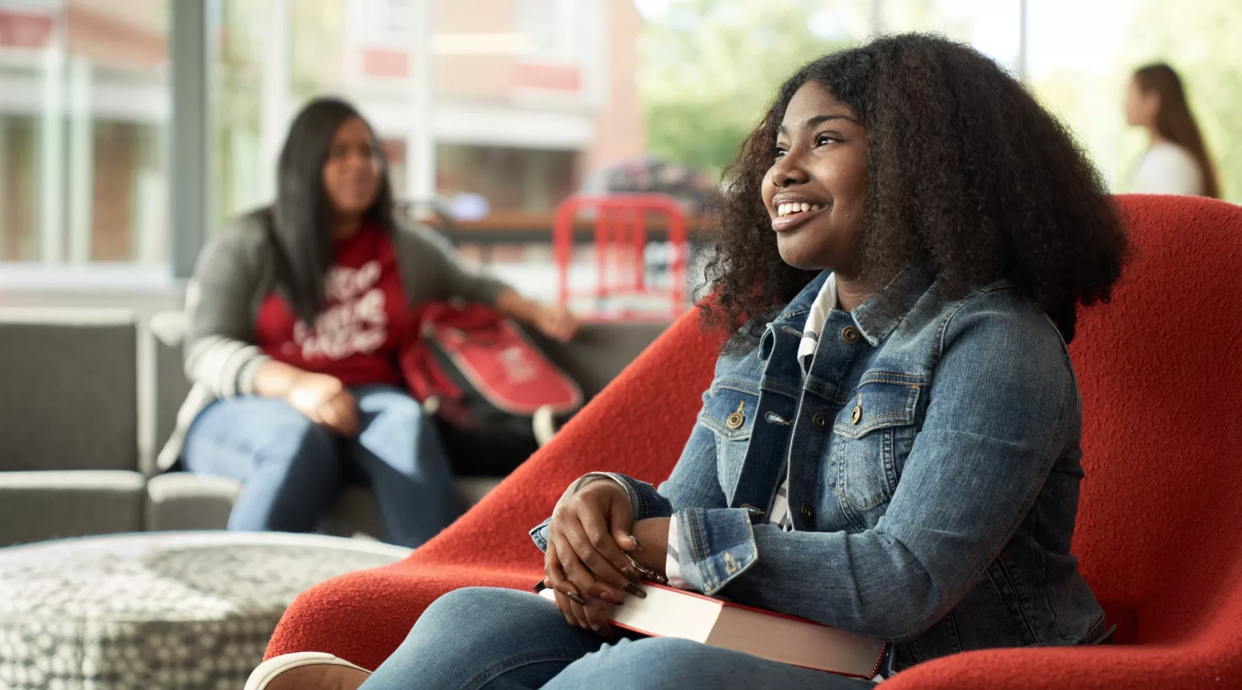 Student, Idaya Gager, sits in a red chair as she poses for campaign.