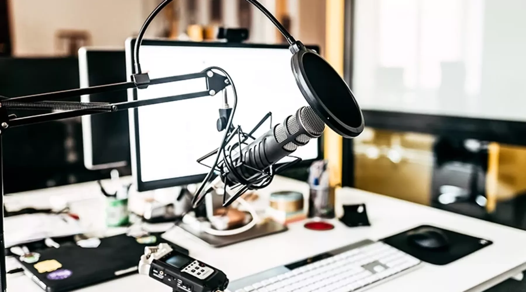 Podcast recording studio with microphone, desktop computer, and other various recording equipment.
