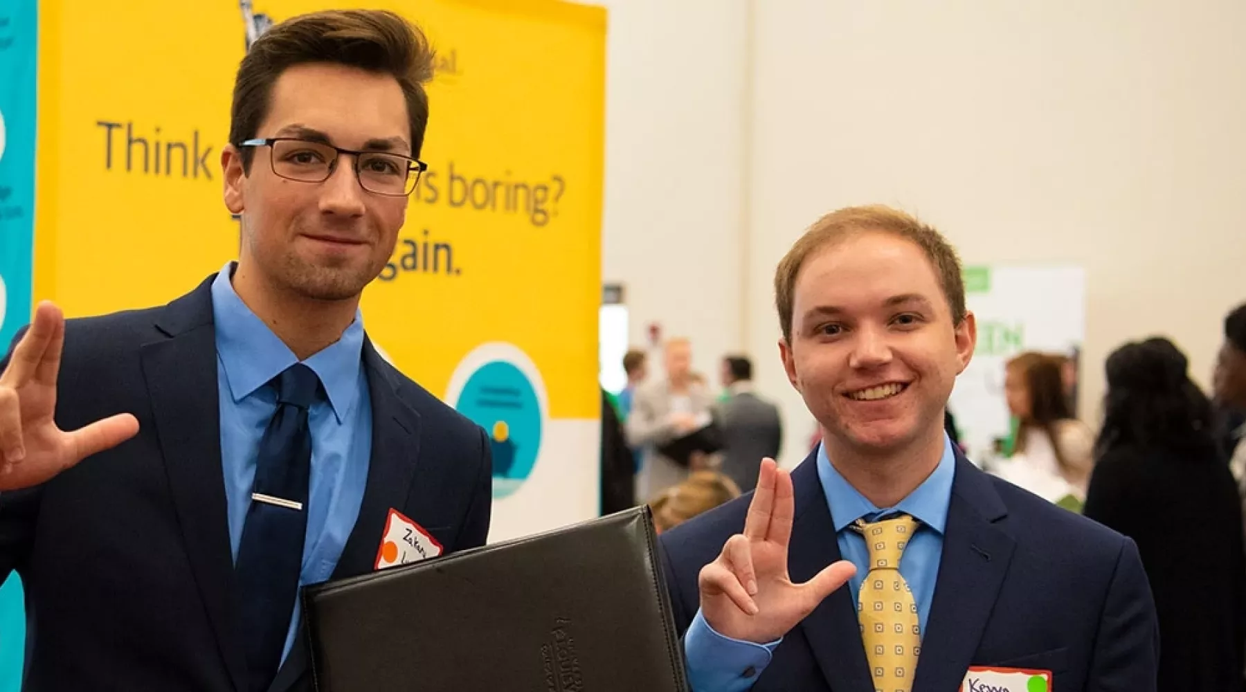 Two BBA students dressed in suits throwing L's up at the College of Business Career Fair.