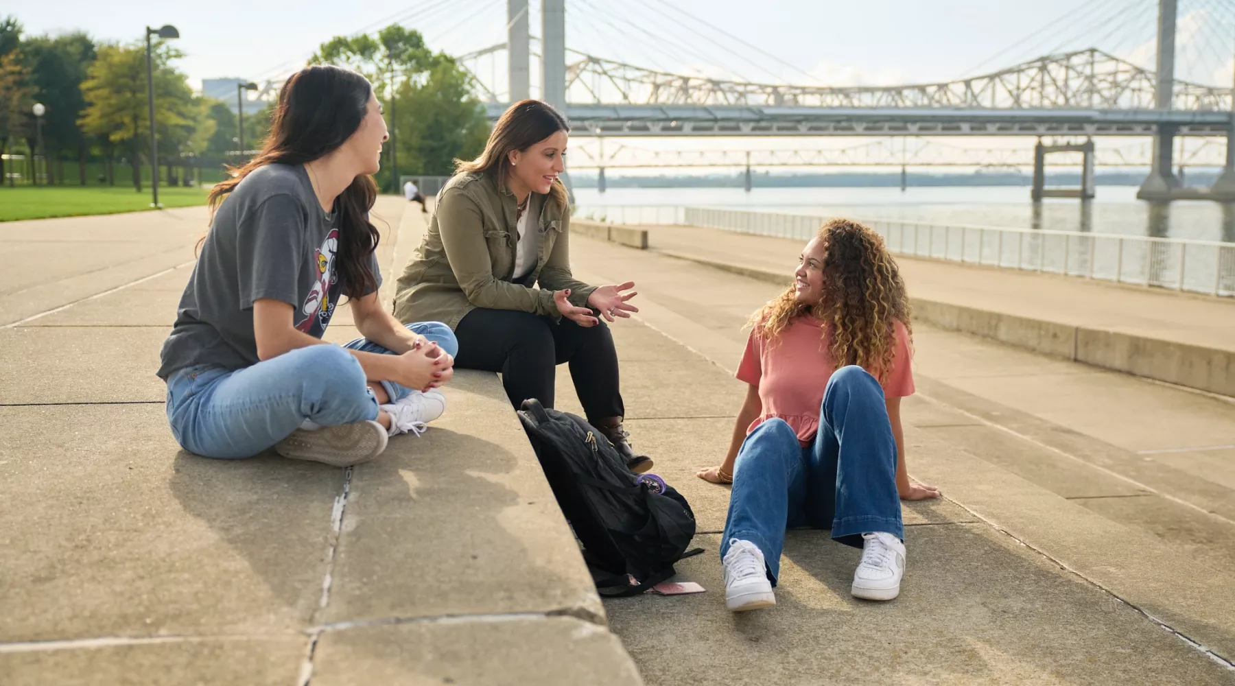 Three students talking on the steps at Waterfront Park in downtown Louisville.