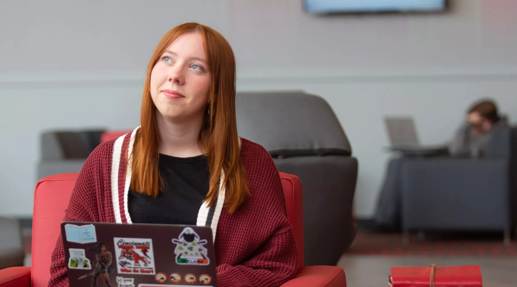 A student pauses in thought while working on a laptop in the Belknap Academic Building