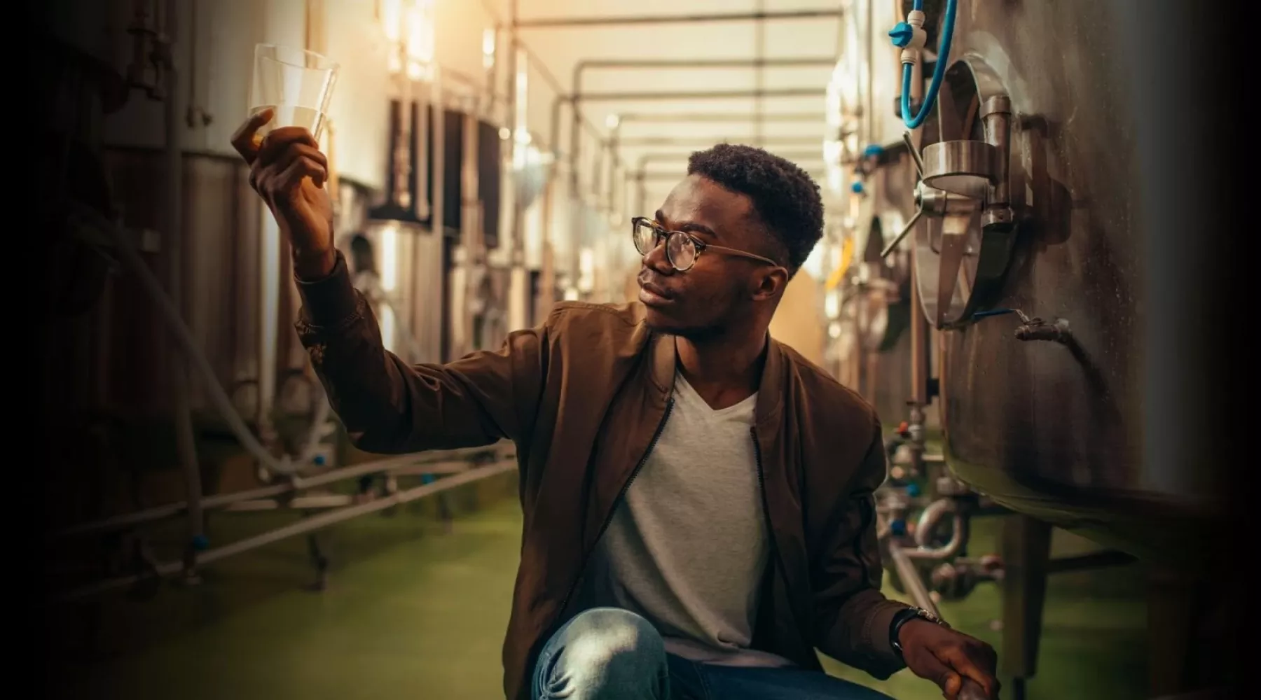 Man analyzes alcohol next to distillery equipment