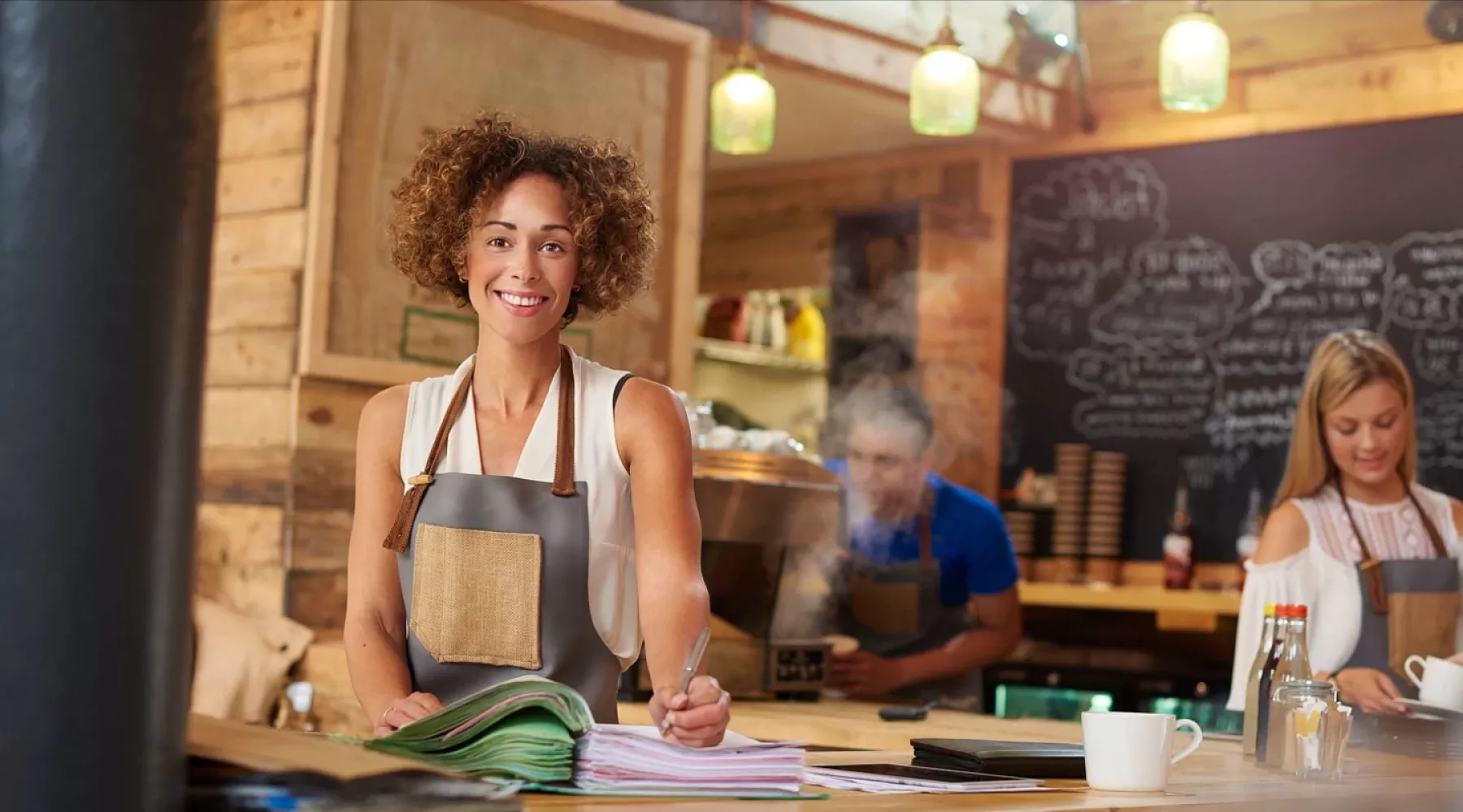 Coffee shop owner in apron working on inventory