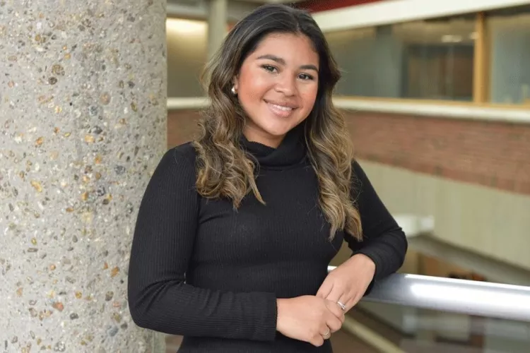 A woman resting her arm on a rail.