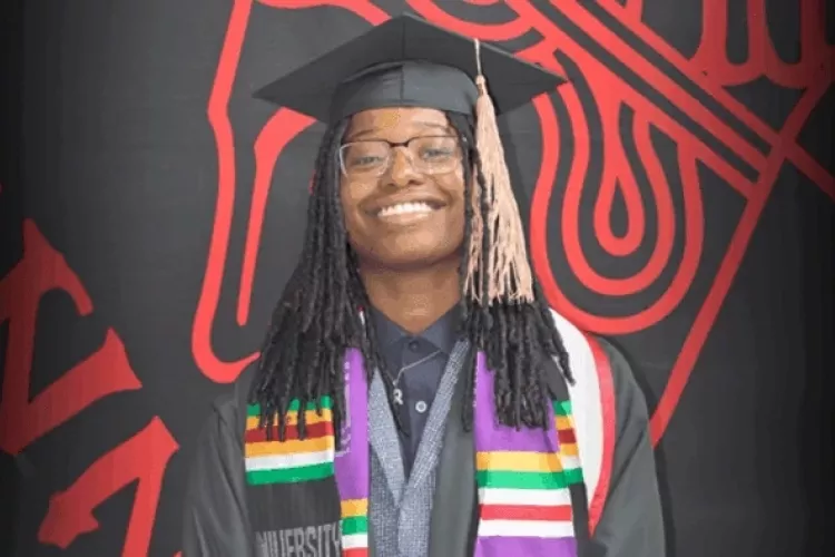 Taylor Price in commencement regalia posing for photo