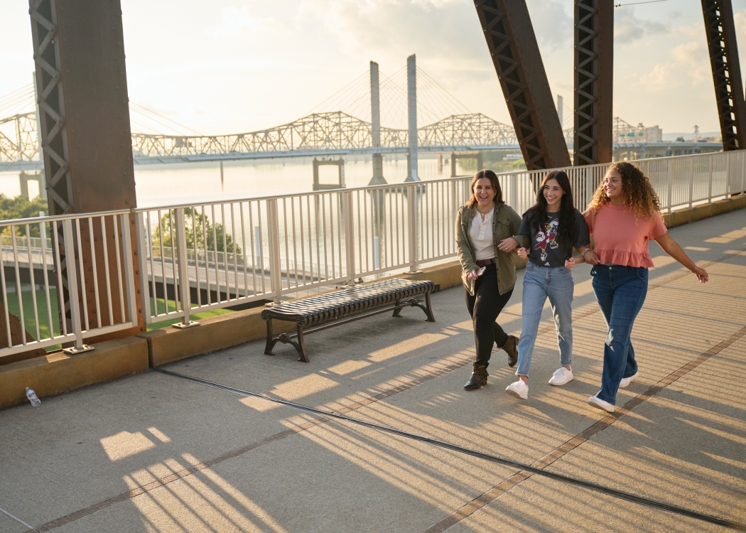 Three students walking and talking on the Big Four Bridge at Waterfront Park in downtown Louisville.