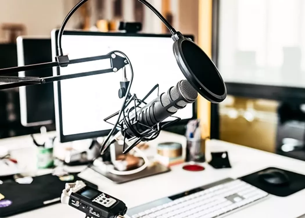 Podcast recording studio with microphone, desktop computer, and other various recording equipment.