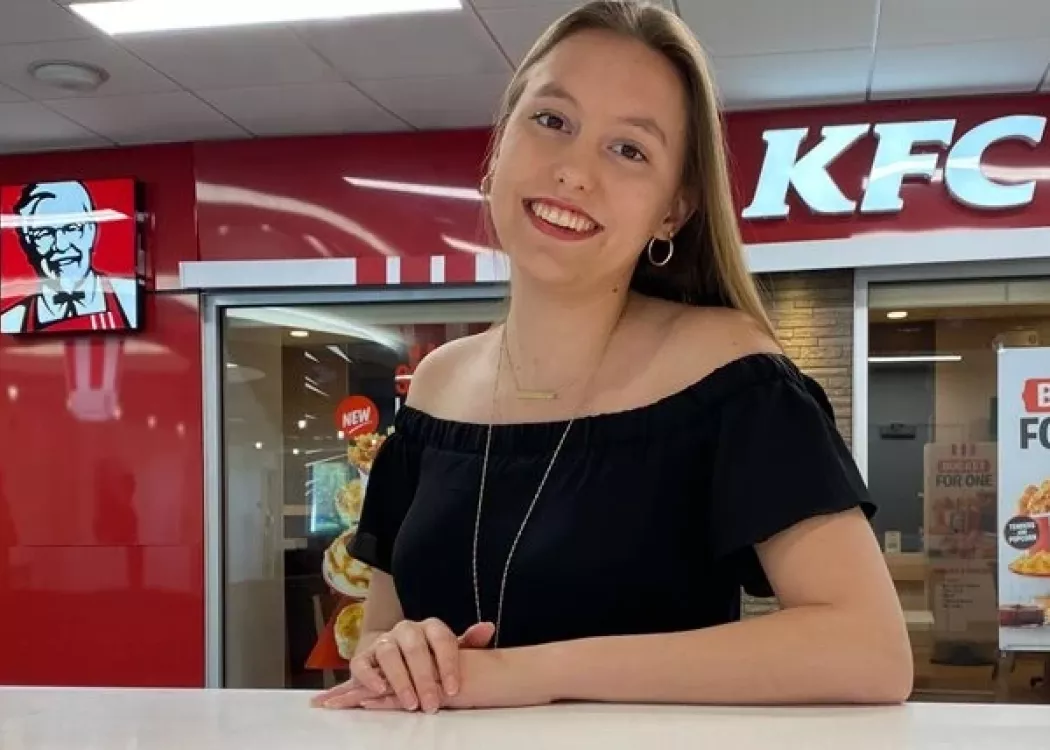 College of Business student, Dacia Berry in front of a Kentucky Fried Chicken restaurant