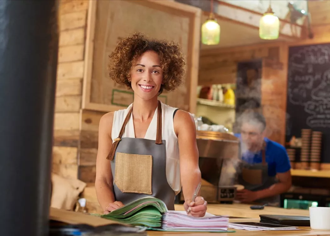 Coffee shop owner in apron working on inventory