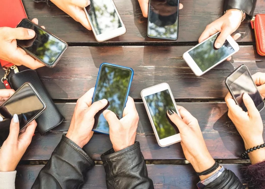 A group of people at an outdoor table using smartphones.