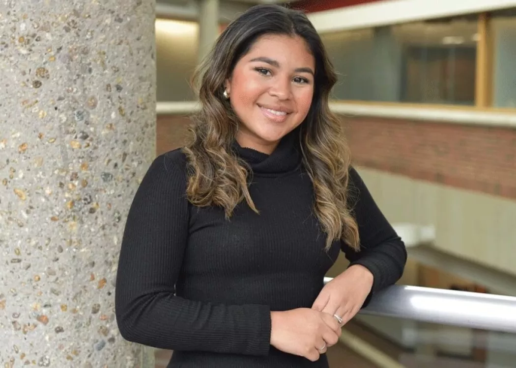 A woman resting her arm on a rail.