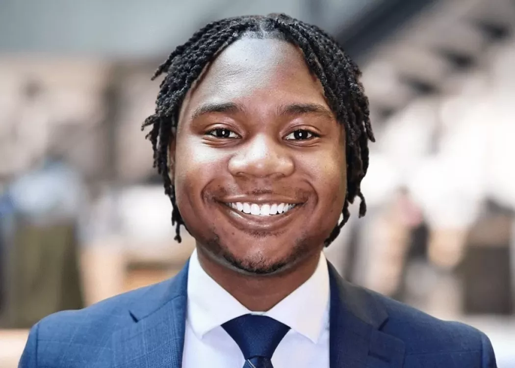 Golden Mashindi in blue suit and tie in front of blurred background.
