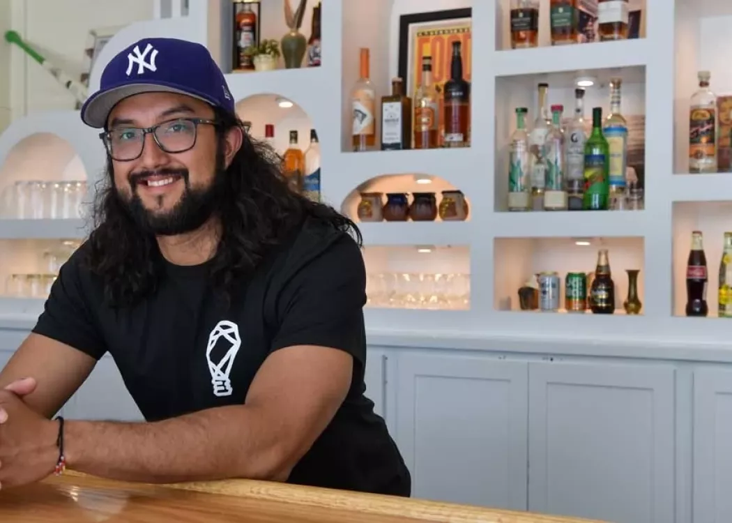 Josh Gonzalez leaning over the bar at his restaurant, FOKO
