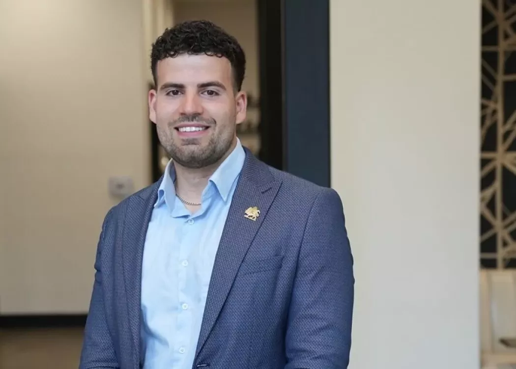 Alumni Nima Asgari in blue coat and shirt posing for photo.