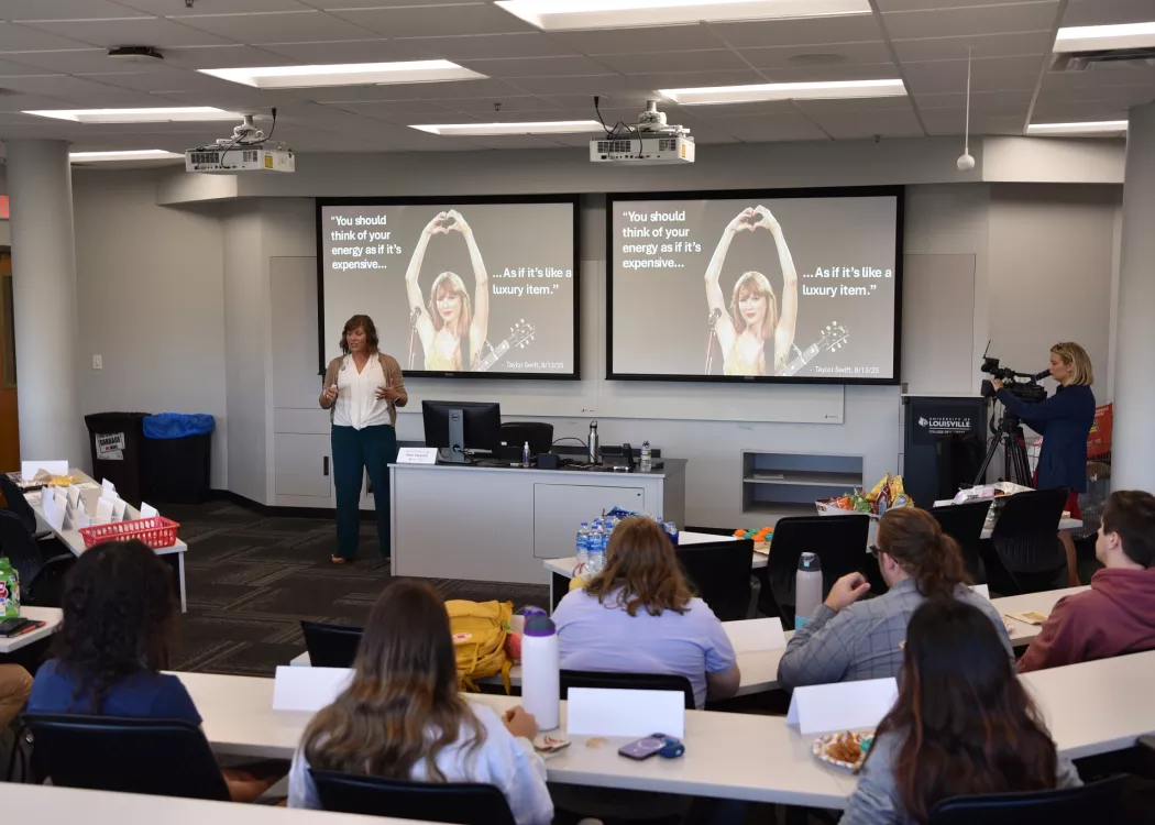 Beth Munnich speaking to a group in front of a presentation with Taylor Swift pictured.