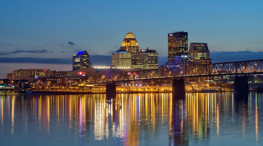 Dusk skyline photo of the Louisville waterfront with light reflections in the Ohio River