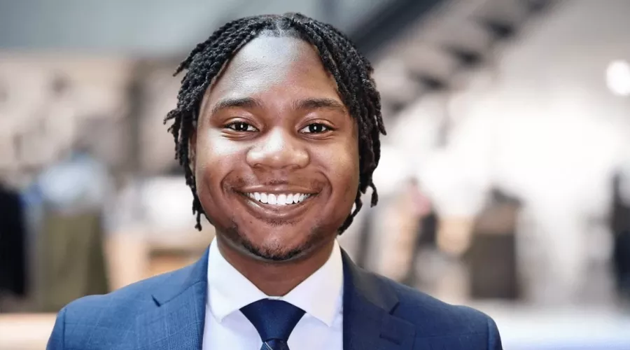 Golden Mashindi in blue suit and tie in front of blurred background.