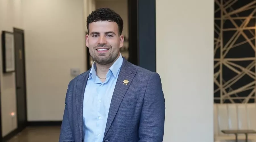 Alumni Nima Asgari in blue coat and shirt posing for photo.