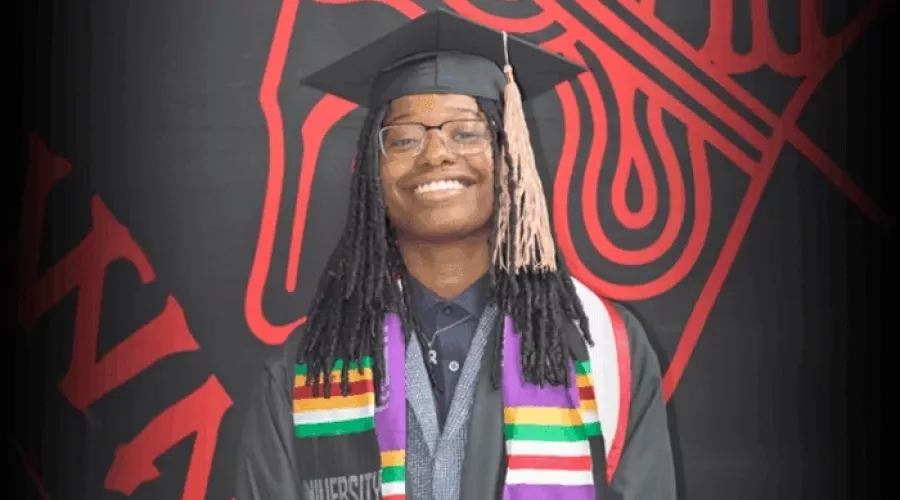 Taylor Price in commencement regalia posing for photo