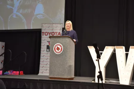A woman presenting from a podium on a stage.